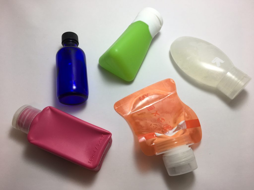 Five colored reusable travel shampoo containers