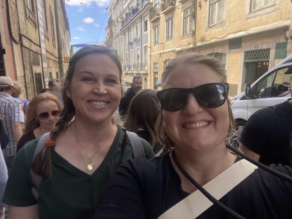 Two friends in the busy streets of Lisbon with bags behind us, which is not how to avoid pickpockets in Lisbon