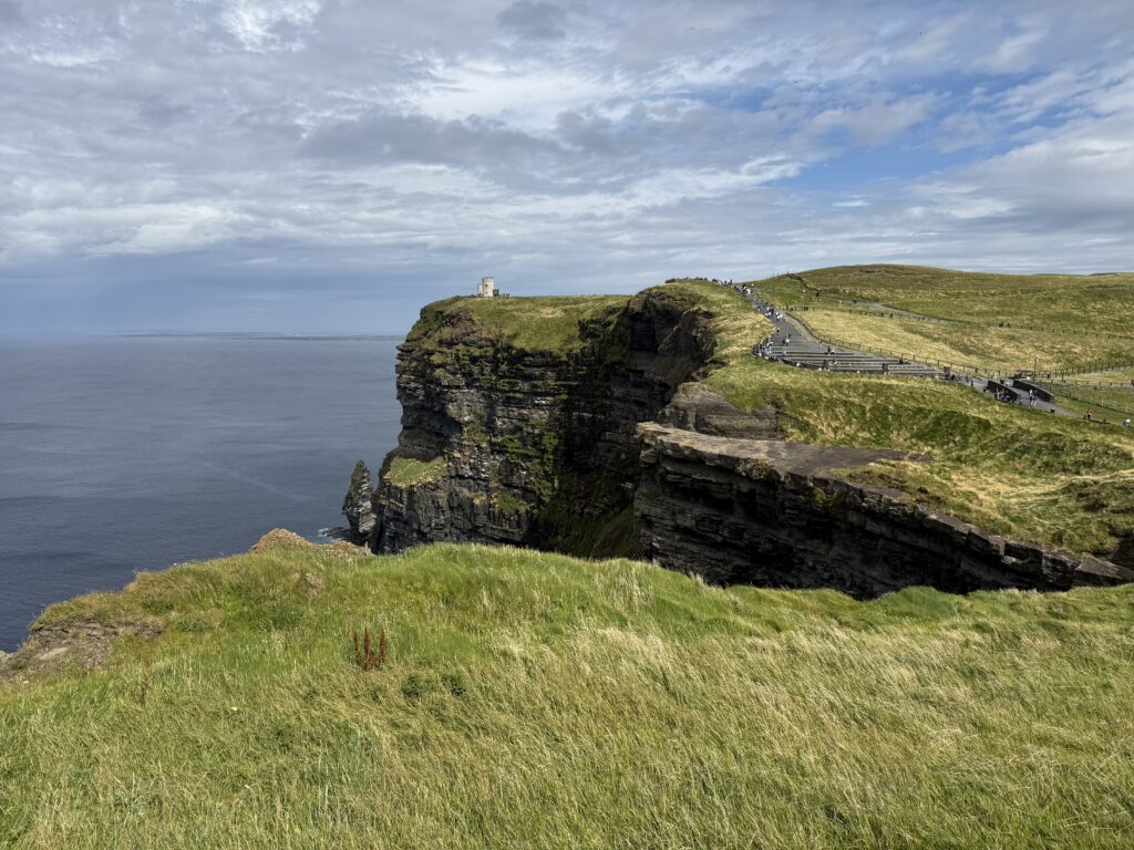 green hill with gray cliffs and blue ocean