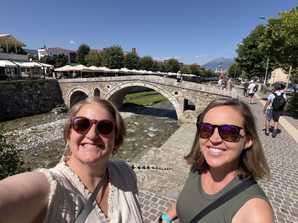 smiling women in front of stone bridge