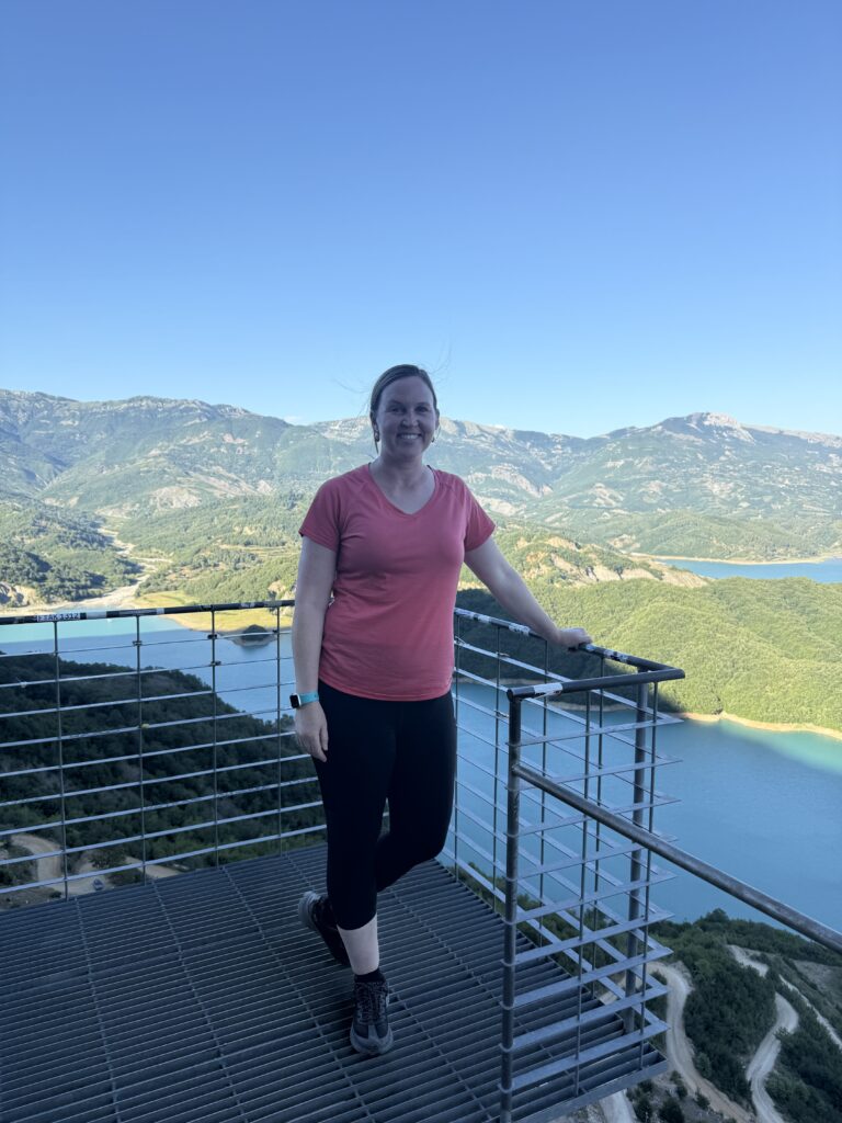 Woman standing on metal gate over blue lake