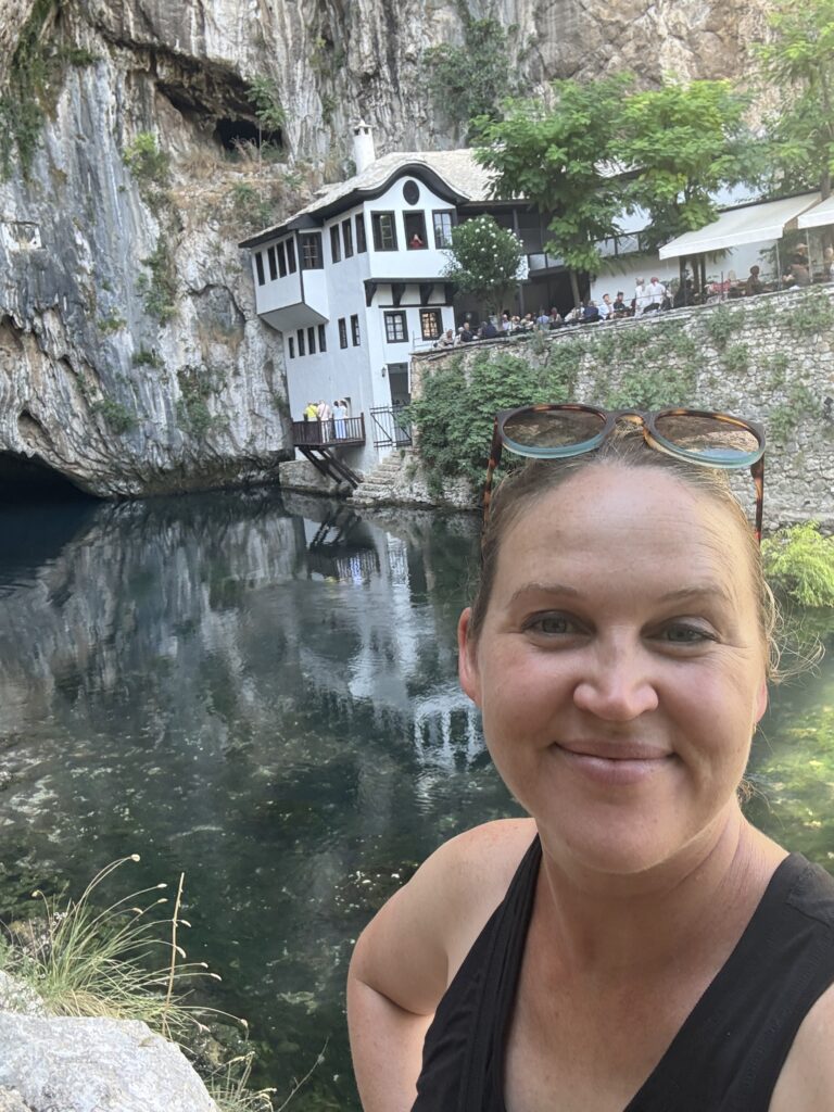 monastery on a river's edge with cliff behind it