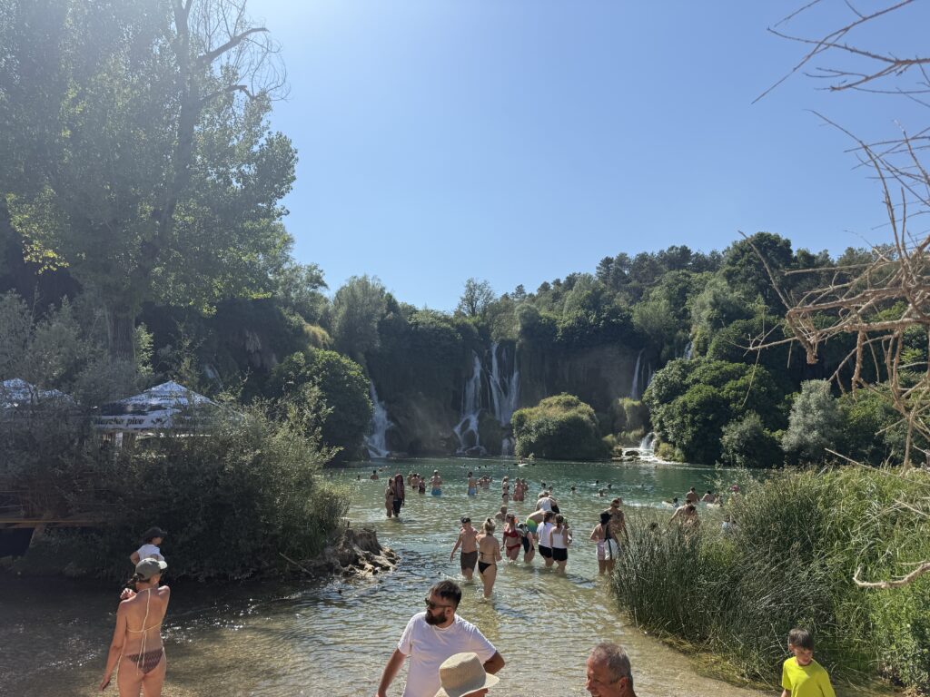 people swimming in water in front of waterfalls